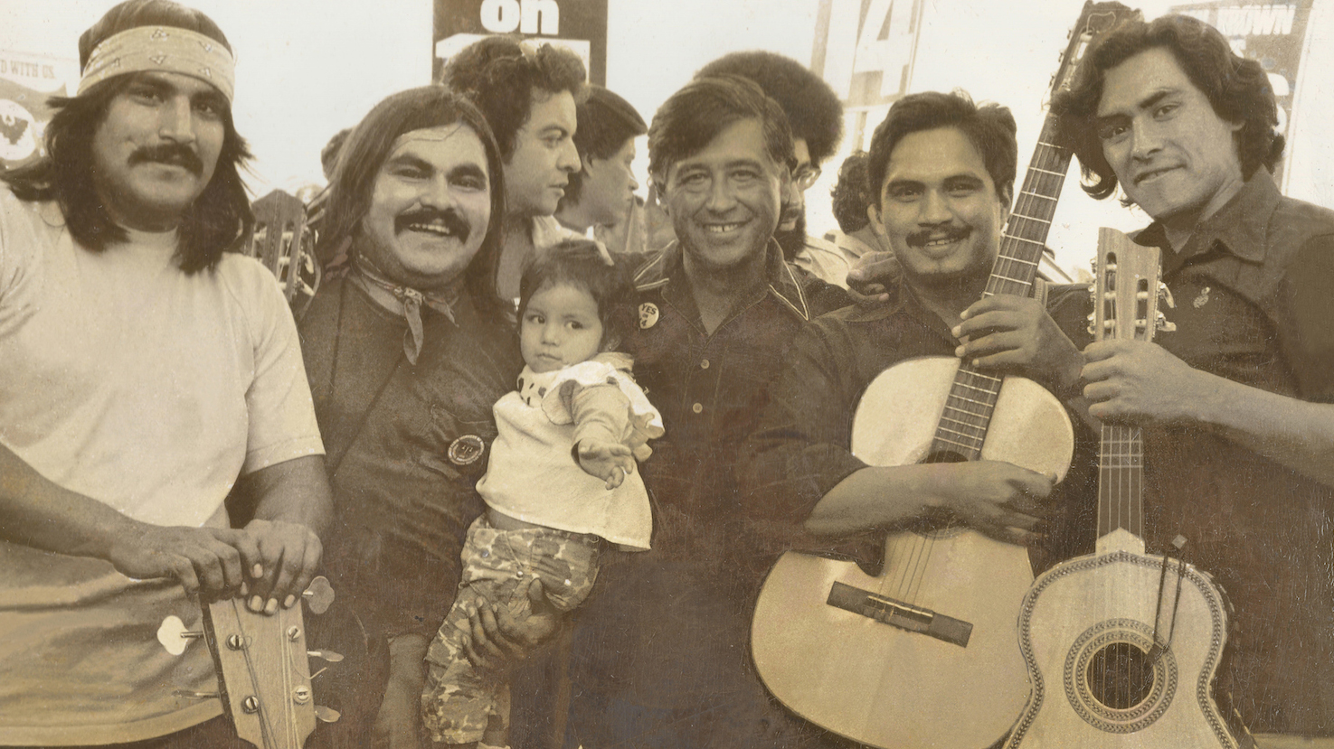 Ramon “Chunky” Sanchez (second from left, holding his daughter) with Cesar Chavez (center), Ricardo Sanchez (at left), Enrique Ramirez (right of Chavez) and unknown musician at far right, ca 1972. Photo courtesy of Ramon “Chunky” Sanchez.